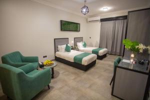 um quarto de hotel com duas camas e duas cadeiras em Karims Hotel em Al Majmaah