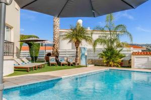 een zwembad met een parasol naast een huis bij Villa Soraya 1 by Ezoria Villas in Coral Bay