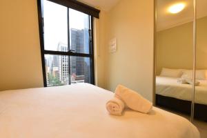 een slaapkamer met een spiegel en een bed met een handdoek bij Rest Collins Tower collection in Melbourne