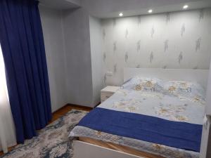 1 dormitorio con cama y cortina azul en Apartment Center 1, en Tashkent