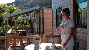 a woman standing next to a table with a plate of food at Camping Bungalow Serra de Prades Resort in Vilanova de Prades