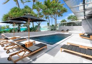 a swimming pool with lounge chairs and an umbrella at 18OB Absolute Beachfront - Noosa Main Beach in Noosa Heads