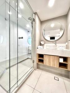 a bathroom with a shower and a sink and a mirror at 18OB Absolute Beachfront - Noosa Main Beach in Noosa Heads