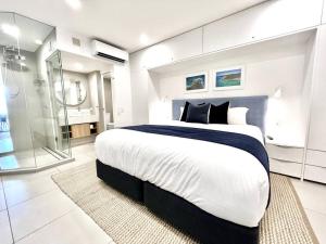 ein Schlafzimmer mit einem großen Bett und einer Glasdusche in der Unterkunft 18OB Absolute Beachfront - Noosa Main Beach in Noosa Heads