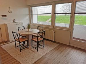 a dining room with a table and chairs and windows at FeWo Meerblick - Schillig in Schillig