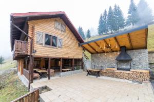 a wooden house with a patio in front of it at Moșia Sofiei in Moieciu de Sus