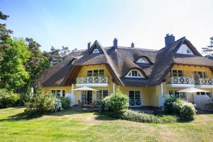 a large yellow house with a thatched roof at Ferienwohnungen Fischland in Dierhagen