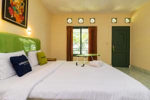 ein Schlafzimmer mit einem großen weißen Bett und einer grünen Tür in der Unterkunft Urbanview Hotel Griya Astoeti 2 Cisarua Puncak in Kopo 2