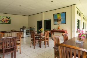 uma sala de jantar com mesas e cadeiras de madeira em Urbanview Hotel Griya Astoeti 2 Cisarua Puncak em Kopo 2