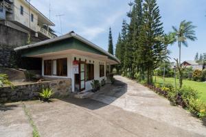 una pequeña casa con un camino junto a un edificio en Urbanview Hotel Griya Astoeti 2 Cisarua Puncak, en Kopo 2