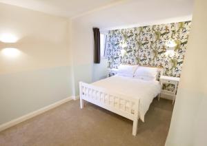 Garden Apartment Winchester في وِنشستير: غرفة نوم بسرير ابيض وورق جدران