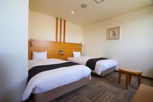 大牟田市にあるホテル ニューガイア オームタガーデンのベッド2台とテーブルが備わるホテルルームです。