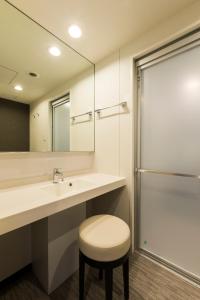 a bathroom with a sink and a stool and a mirror at Via Inn Nagoya Station Tsubaki-cho in Nagoya