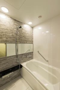 a bathroom with a white tub and a shower at Via Inn Nagoya Station Tsubaki-cho in Nagoya