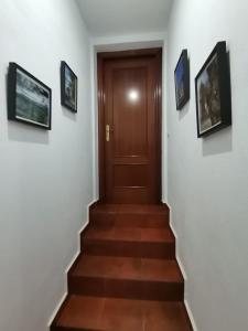 una escalera con una puerta de madera y cuadros en la pared en Casa El Tío Juan, en Cumbres de San Bartolomé