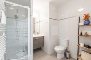 a white bathroom with a shower and a toilet at Bon Voyage by Plaza in Montévrain