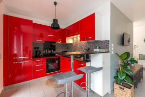 a red kitchen with red cabinets and stools at Bon Voyage by Plaza in Montévrain