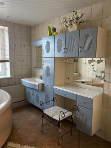 a bathroom with blue cabinets and a sink and a tub at The Baltic coast apartment in Ventspils
