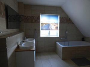baño con lavabo, bañera y ventana en komfortables Ferienhaus Allee, en Krummin