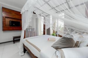 a bedroom with a white canopy bed and a tv at Saffron Hotel Unawatuna in Unawatuna +56 photos