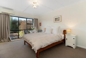ワナカにあるTownside Treat - Wanaka Holiday Homeのベッドと大きな窓のある寝室