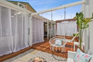 a screened porch with a wicker chair on a deck at Private Outdoor Spa, Fire Pit - THE RETREAT COOLUM BEACH in Coolum Beach