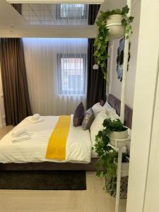 ein Schlafzimmer mit einem Bett mit einer Pflanze drum herum in der Unterkunft Luxury City Studios in Curtea de Argeş