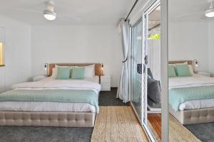 1 dormitorio con 2 camas y espejo en Private Outdoor Spa, Fire Pit - THE RETREAT COOLUM BEACH en Coolum Beach