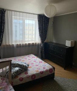 a bedroom with a bed and a dresser and a window at The Baltic coast apartment in Ventspils