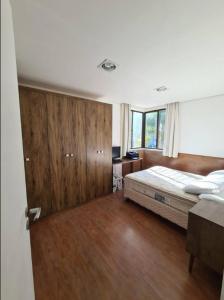 1 dormitorio con 1 cama y suelo de madera en Jurerê Beira Mar Residence, en Florianópolis