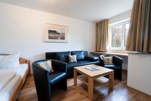 ein Hotelzimmer mit einem Bett, 2 Stühlen und einem Tisch in der Unterkunft Ferienwohnung Sandburg App 27a in Timmendorfer Strand