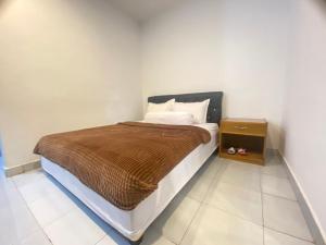 a bedroom with a bed with a brown blanket and a night stand at Villa Matano Sorowako 2 Redpartner in Saroako