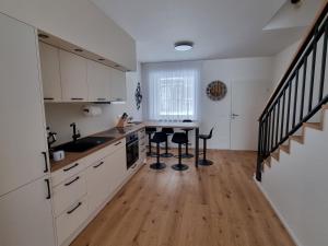 a kitchen with white cabinets and a table and stools at Apartment Max in Loučná pod Klínovcem