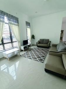 ein Wohnzimmer mit einem Sofa und einem TV in der Unterkunft Homestay Kemaman Fyna07 Banglo Mewah 5 KM Dari Pantai Kijal in Kijal