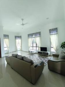 ein Wohnzimmer mit 2 Sofas und einem TV in der Unterkunft Homestay Kemaman Fyna07 Banglo Mewah 5 KM Dari Pantai Kijal in Kijal