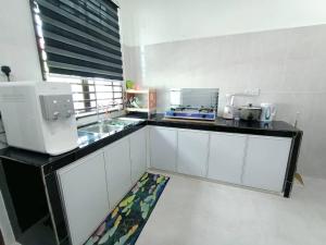 eine Küche mit weißen Schränken und einer Arbeitsplatte in der Unterkunft Homestay Kemaman Fyna07 Banglo Mewah 5 KM Dari Pantai Kijal in Kijal