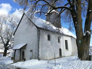 une vieille église blanche avec de la neige sur son toit dans l'établissement Angi's Apartment, à Sankt Lorenzen ob Murau