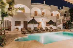 a swimming pool with chairs and a building at Casa Louka in Saly Portudal