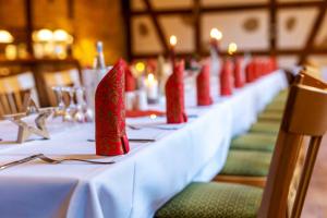 - une longue table avec des serviettes rouges dans l'établissement Land gut Hotel Hermann, à Bentwisch