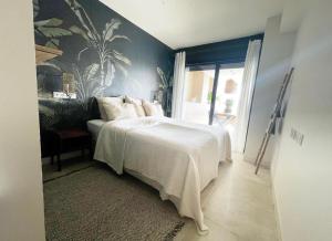 1 dormitorio con 1 cama con edredón blanco en KURA Aprtmnt, en La Cala de Mijas