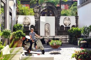 a woman riding a scooter in front of a building at Hotel Piazza Bellini & Apartments in Naples