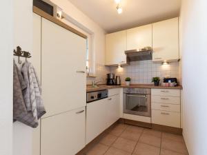 una pequeña cocina con armarios y electrodomésticos blancos en Ferienhaus To Hus en Vieregge
