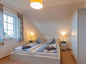 a bedroom with a bed with two lamps and a window at Ferienhaus To Hus in Vieregge