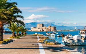 a dock with boats and a castle in the water at Marina's Bright Getaway - Nafplio Center House in Nafplio