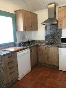 エル・ロシオにあるLa Cabaña de Doñanaのキッチン(木製キャビネット、白い食器洗い機付)