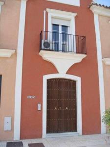 um edifício com uma porta castanha e uma varanda em Casa La Rocina Almonte em Almonte