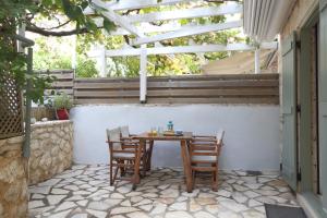 stół i krzesła na patio z pergolą w obiekcie Wild Sea Apartments w mieście Agios Nikitas