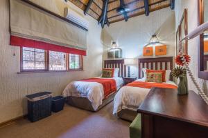 a bedroom with two beds and a desk and two windows at Kruger Park Lodge Unit No 521 with Private Pool in Hazyview