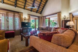 een woonkamer met een bank en een tv bij Kruger Park Lodge Unit No 521 with Private Pool in Hazyview