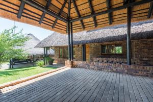 ein Backsteingebäude mit einem Strohdach und einer Terrasse in der Unterkunft Kruger Park Lodge Unit No 521 with Private Pool in Hazyview